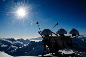Measuring instruments in snow-covered mountains against a blue sky and the sun